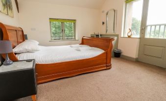 a large bed with white sheets and a wooden headboard is in a room with a window at Lakeside Cottage