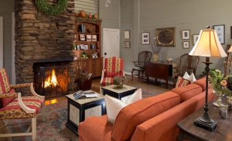 a cozy living room with a fireplace , a couch , and a dining table in the background at Glen-Ella Springs Inn