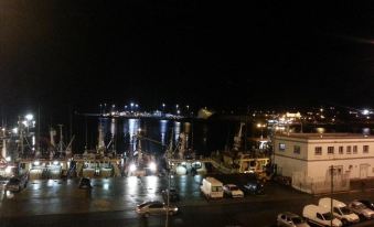 a bustling harbor at night , with numerous boats docked in the water and lights illuminating the area at Tara Hotel