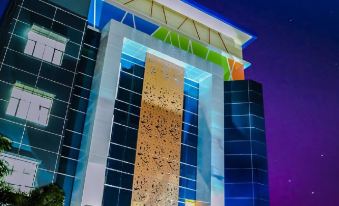 a modern building with a blue and gold facade is illuminated against the night sky at De Baghraf by Amithya