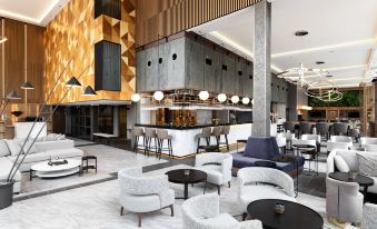 a modern hotel lobby with various seating options , including couches and chairs , as well as a bar area at AC Hotel Stockholm Ulriksdal