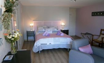 a well - decorated bedroom with a bed , nightstands , and a couch , all set against a white wall at La Clef des Champs