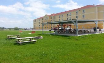 a large building with a covered patio area , and picnic tables surrounded by green grass at Amelia Extended Stay & Hotel