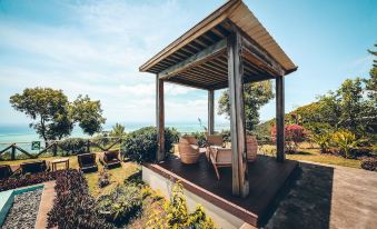 a wooden gazebo surrounded by lush greenery , with a view of the ocean in the distance at Chalets Chamarel