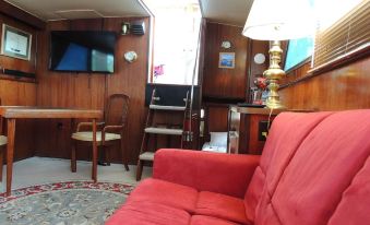 a living room with a red couch , wooden walls , and a television mounted on the wall at Cookie B