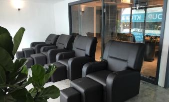 a room filled with black leather recliners and ottomans , likely used in a lounge setting at Z Hotel