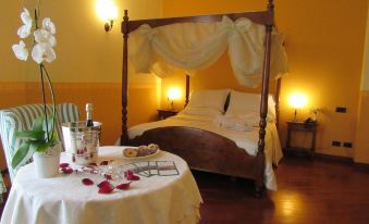 a bedroom with a bed covered in white sheets and a canopy , next to a dining table with wine glasses and a bottle of wine at Green Hotel