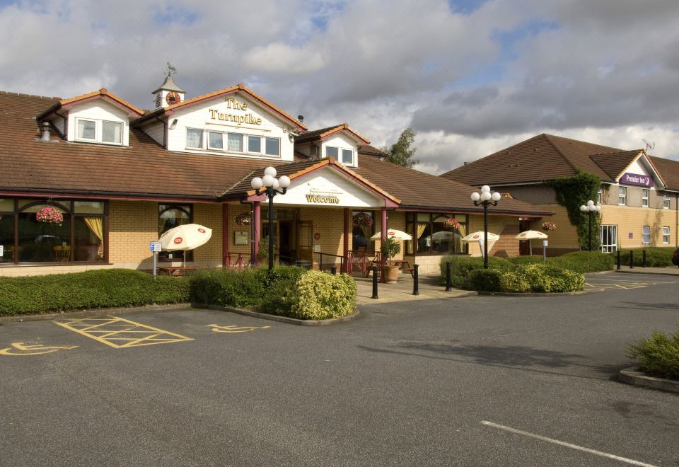 a large building with a red roof and white columns is surrounded by a parking lot at Premier Inn Pontefract North