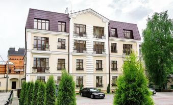 a large white apartment building with multiple balconies and windows , surrounded by trees and a black car parked in front at Metropol Hotel