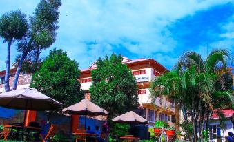 a large building with red walls and a green lawn in front of it , surrounded by trees at Calabash Hotel