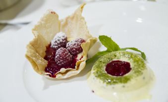 a white plate with a cup of ice cream and a bowl filled with raspberries at Hotel Alpino