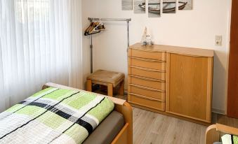 a room with a wooden dresser , a bed with a green and white striped comforter , and several paintings on the wall at Christine