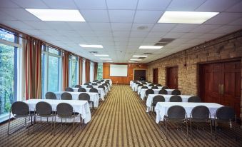 a large conference room with rows of tables and chairs , a screen on the wall , and windows at Cumberland Falls State Resort Park