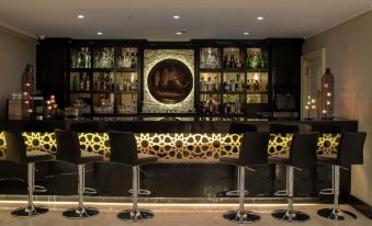 a bar area with a long wooden counter , several stools , and a variety of bottles and glasses on display at DoubleTree by Hilton Gaziantep