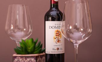 a bottle of domb wine is placed on a table between two glasses , with a potted plant nearby at Pousada Tesouro de MInas