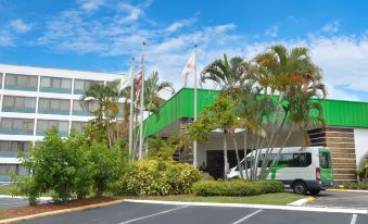 a green building with flags flying in front of it , surrounded by palm trees and other greenery at Holiday Inn ST. Petersburg N- Clearwater