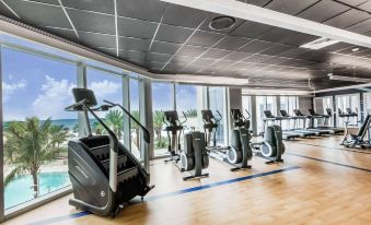 a gym with various exercise equipment , including treadmills and stationary bikes , is seen through large windows at Wyndham Grand Clearwater Beach