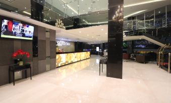 a modern hotel lobby with a large glass elevator and a reception desk in the center at Pakons Prime Hotel