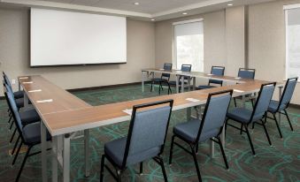 a conference room with a long table and several chairs , all facing a large screen on the wall at Home2 Suites by Hilton Marysville