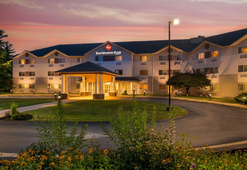 a large hotel with a flower garden in front , and the sun setting in the background at Best Western Plus Executive Court Inn  Conference Center