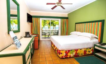a modern hotel room with green walls , white bed , and orange furniture , along with a balcony overlooking the ocean at Barcelo Tambor - All Inclusive