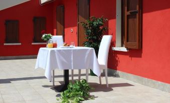 a white table with a white tablecloth and two chairs in front of a red building at Hotel Savoia
