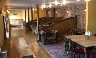 a large room with wooden floors and tables , chairs , and a staircase leading to another area at The Carew Arms