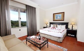 a large bed with a white comforter and rose petals on it is in a room with a window at Melia Panama Canal