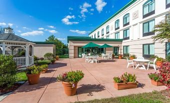 a large white building with green trim , surrounded by potted plants and chairs on a patio area at Holiday Inn Belcamp - Aberdeen Area