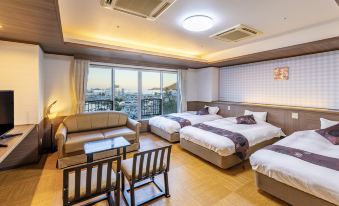 a modern hotel room with three beds , two nightstands , a table , and a window view of the city at Todaya