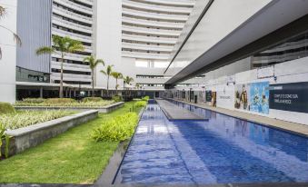 a large swimming pool is surrounded by a walkway and palm trees in an open space at Slaviero Campina Grande