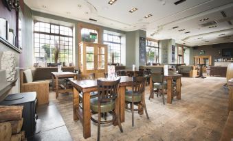 a large , open dining area with wooden tables and chairs arranged in a restaurant setting at Columba Hotel Inverness by Compass Hospitality