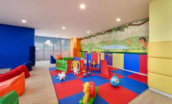 a colorful playroom with a variety of toys and equipment , including a slide , for children to play on at Oakwood Apartments PIK Jakarta