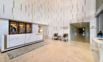 a modern office lobby with white and gold walls , marble floors , and two marble reception desks at Oakwood Apartments Pik Jakarta