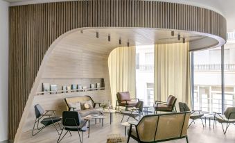 a modern living room with wooden furniture , including a couch , chairs , and a coffee table at Okko Hotels Toulon Centre