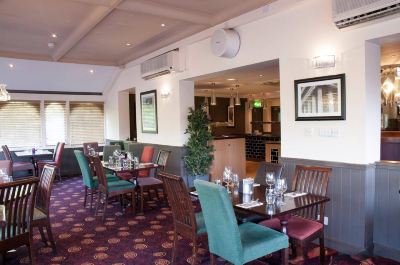 a restaurant with several tables and chairs , a christmas tree in the corner , and artwork on the walls at Village Hotel Liverpool