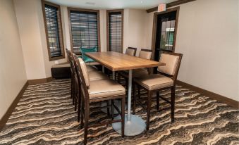 a wooden table with chairs is set up in a room with large windows and gray and white patterned carpet at Staybridge Suites Washington DC East - Largo