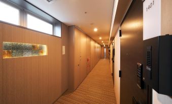 There is a long hallway with doors along the walls, and at one end, there is an empty room at Stayat Osaka Shinsaibashi East