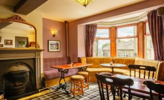 a cozy living room with a fireplace , multiple chairs , and a dining table in the background at Cross Keys