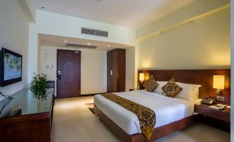 a large bed with a white comforter and brown blanket is in the middle of a room at Hotel Grand Park Barishal