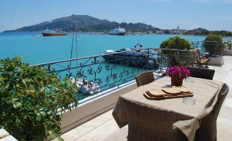 a table with a vase of flowers is set on a balcony overlooking the water at Dali