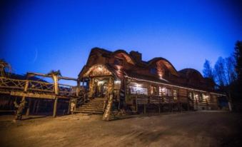 a large wooden building with a thatched roof is lit up at night , surrounded by a desert landscape at Troll