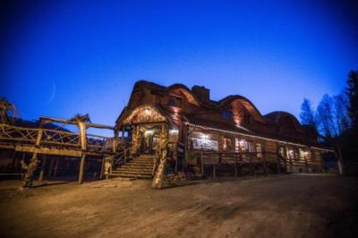 a large wooden building , possibly a log cabin , surrounded by trees and lit up at night at Troll