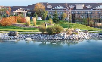 a serene view of a resort with buildings , trees , and water , reflecting the scene in the glass walls at Georgian Bay Hotel, Trademark Collection by Wyndham