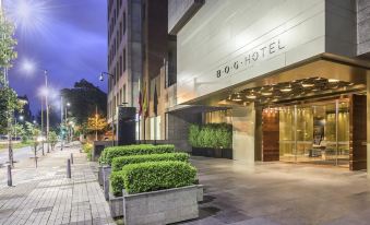 "a modern building with the name "" 8 0 6 hotel "" on it , surrounded by greenery and lit up at night" at Bog Hotel