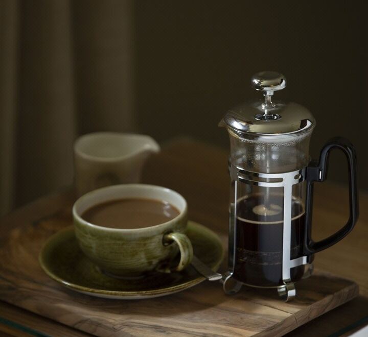 a cup of coffee and a glass jar with a handle are placed on a wooden table at Isle of Mull Hotel and Spa