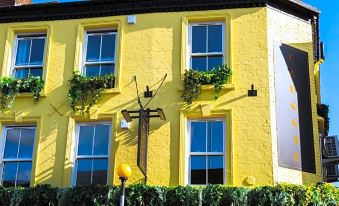 a yellow building with green plants growing on the windows , creating a vibrant and inviting atmosphere at Caboose