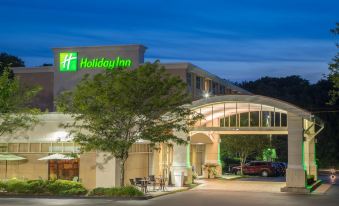 a holiday inn hotel at night , illuminated by green lights , with cars parked outside and trees in the background at Holiday Inn South Kingstown (Newport Area)