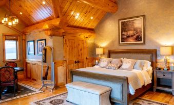 a cozy bedroom with a wooden bed , a bench , and a painting on the wall at Coyote Bluff Estate