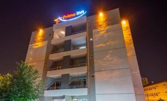 "a building with a sign that says "" prime inn "" is illuminated at night , with multiple balconies and trees in the background" at Prime Inn